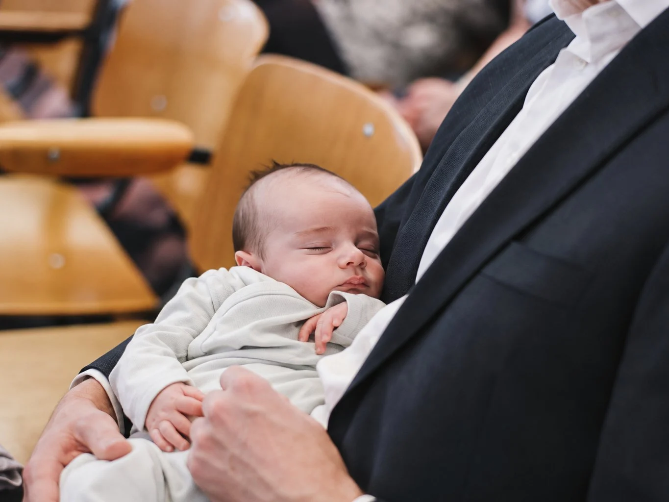Een baby slaapt op de arm van zijn vader tijdens de kerkdienst in De Ark